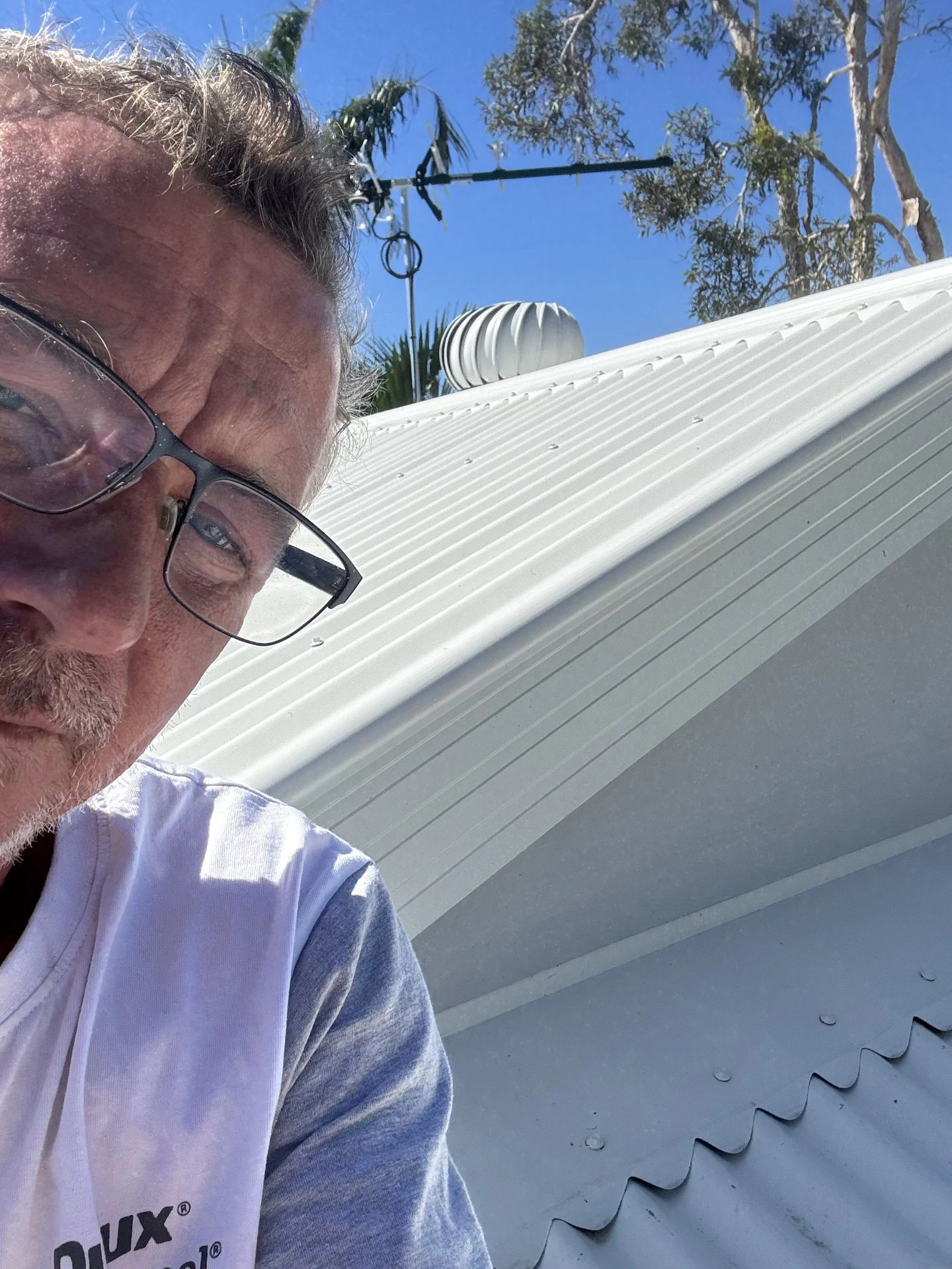 Painter beside a freshly finished light-coloured metal roof