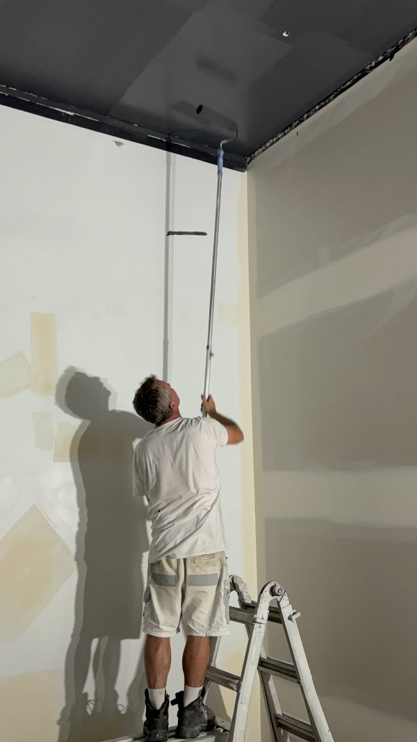 Painter preparing a tall interior wall