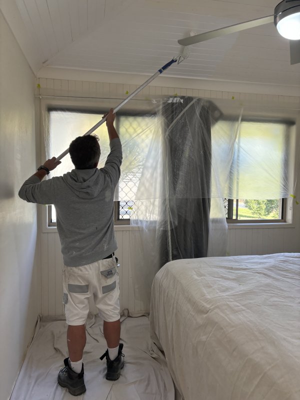 Painter completing a bright bedroom repaint