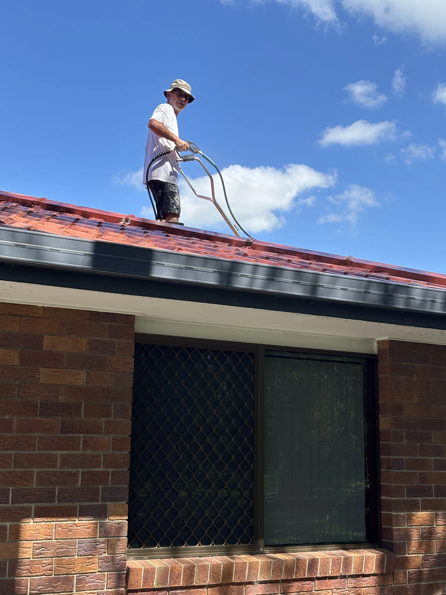 Painter cleaning a tiled roof before coating